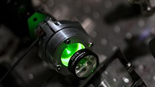 Close up image of an experiment with a green optical laser.